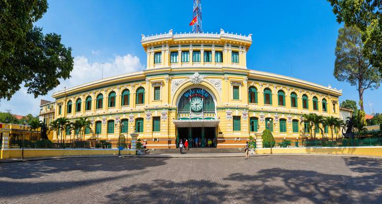 Ikonisches Postgebäude mit gelber Fassade und Uhr.