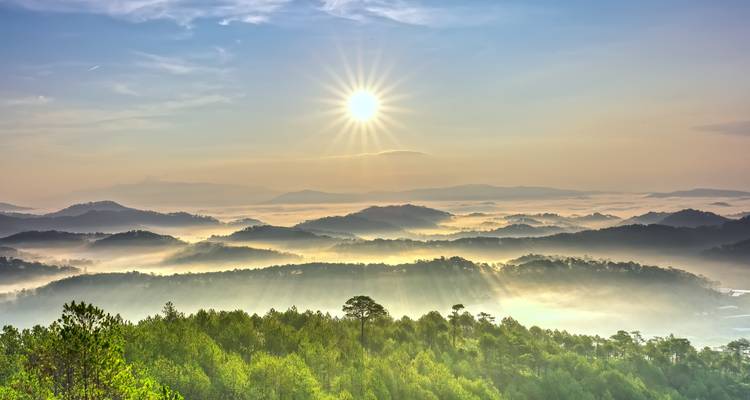 Sonnenaufgang über nebligen Bergen und Wäldern.