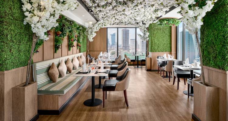 Interior de restaurante con decoración floral y vista a la ciudad.