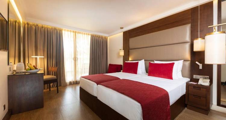 Moderne hotelkamer met twee aparte bedden en rode accenten.