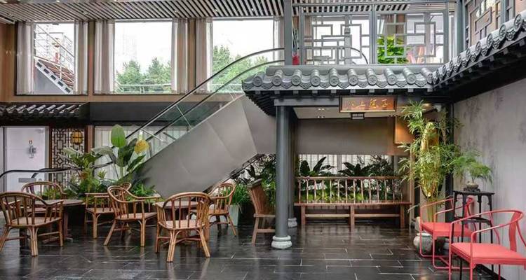 Stilvolle Kreuzfahrt-Lounge mit Bambuspflanzen, einer Treppe und traditionellen chinesischen Flechtmustern.