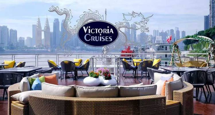 Außenlounge-Deck eines Schiffes der Victoria Cruises mit Stadtskyline im Hintergrund und Drachenlogo.