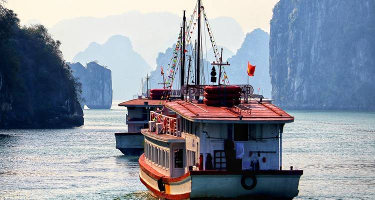 Zwei große Boote auf einem ruhigen Meer, umgeben von Kalkstein-Karst.