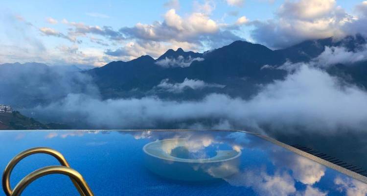 Overloopzwembad met uitzicht op de bergen en wolken.