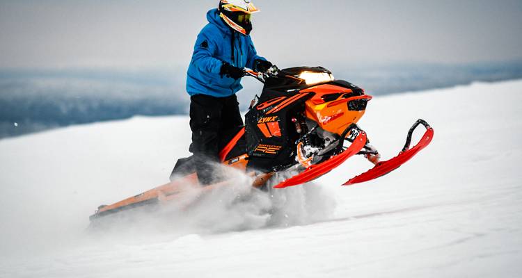 Personne conduisant une motoneige sur un terrain enneigé.