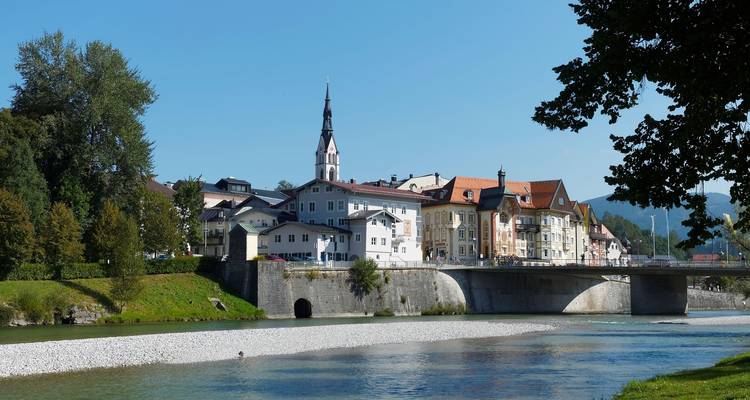 Eine Stadtlandschaft mit einer Brücke über einem Fluss und Bergen im Hintergrund.