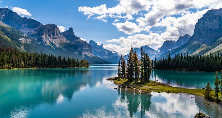 Lac tranquille entouré de montagnes avec une île au centre.