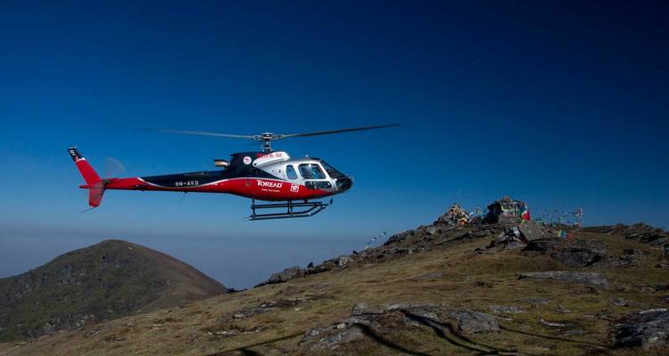 Helicóptero volando sobre una cresta montañosa.