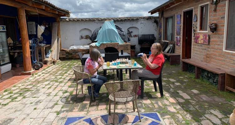 Deux femmes assises dehors sur une terrasse avec du matériel d'artisanat.