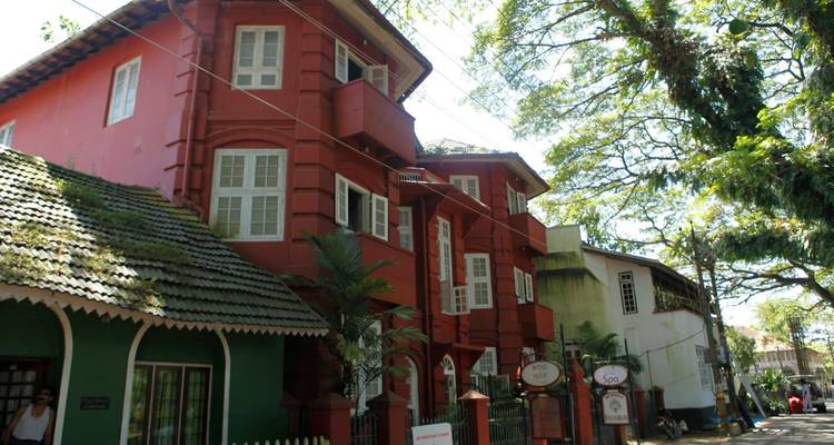 Edificio rojo de estilo colonial entre árboles.