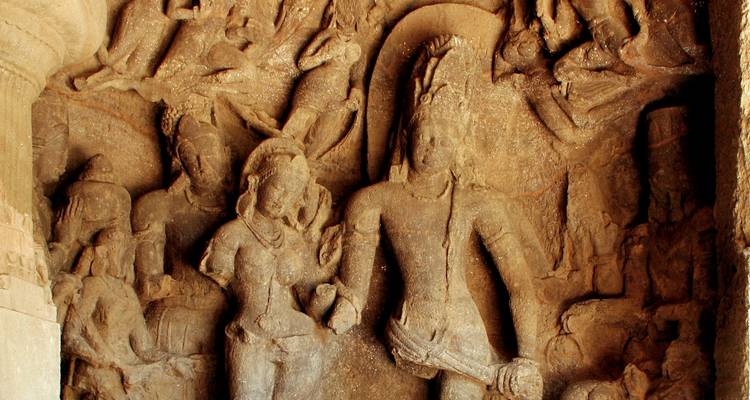 Ancient stone carvings depicting figures in a rock cave setting.
