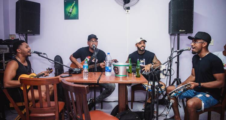 Pequeña banda de samba tocando con guitarras, cavaquiño y pandereta en un acogedor bar