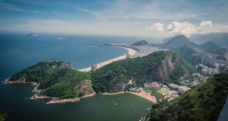 Vista aérea panorámica sobre la playa de Copacabana, el Pan de Azúcar y las exuberantes colinas que se encuentran con el Océano Atlántico