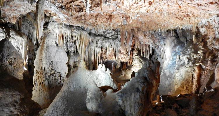 Vue rapprochée de formations spectaculaires de grottes avec stalactites et stalagmites en lumière tamisée.