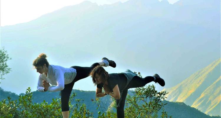 Twee mensen die yoga beoefenen met uitzicht op de bergen.