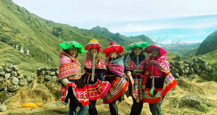 Vrouwen in kleurrijke traditionele kledij poserend met bergen.