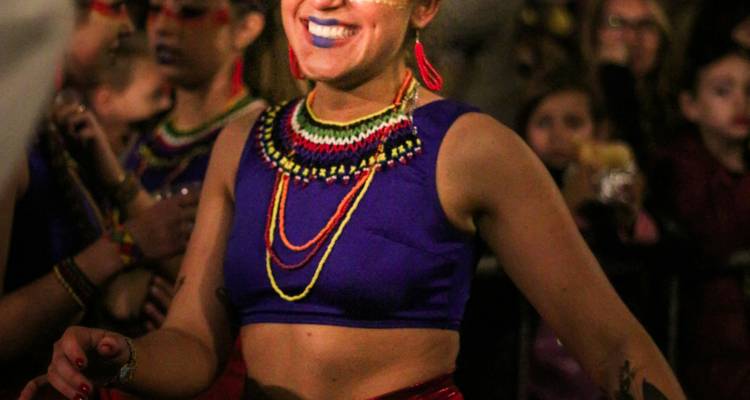 Personne souriante en vêtements colorés à un festival.