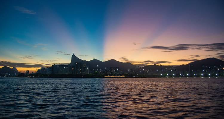 Coucher de soleil dramatique sur la ligne d'horizon de Rio avec la silhouette du Corcovado et des rayons s'étendant à travers le ciel.