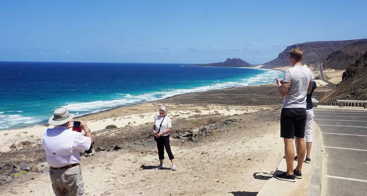 Menschen, die an einem Küstenaussichtspunkt mit blauem Meer und Straße Fotos machen.
