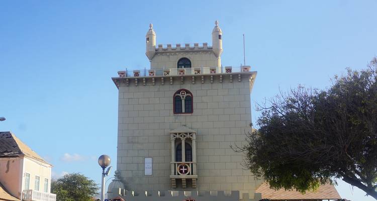 Historisches Steingebäude mit dekorativen Elementen und einem Baum in der Nähe.