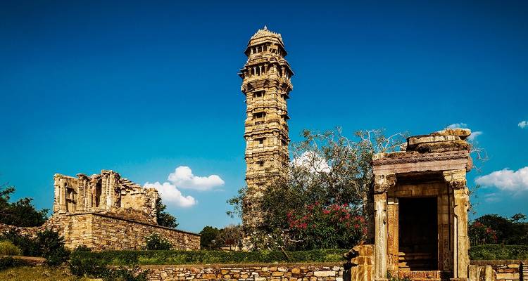 Ein hoher alter Turm und Ruinenstrukturen unter einem klaren blauen Himmel.