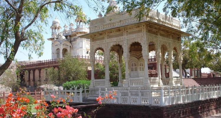 Ein kunstvoller weißer Pavillon mit kunstvollen Schnitzereien, umgeben von Bäumen.