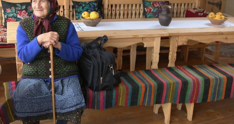 Oudere vrouw zittend in een traditionele kamer.