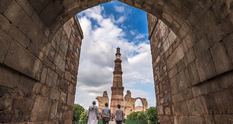 Touristen, die durch einen antiken Torbogen mit einem Turm gehen.