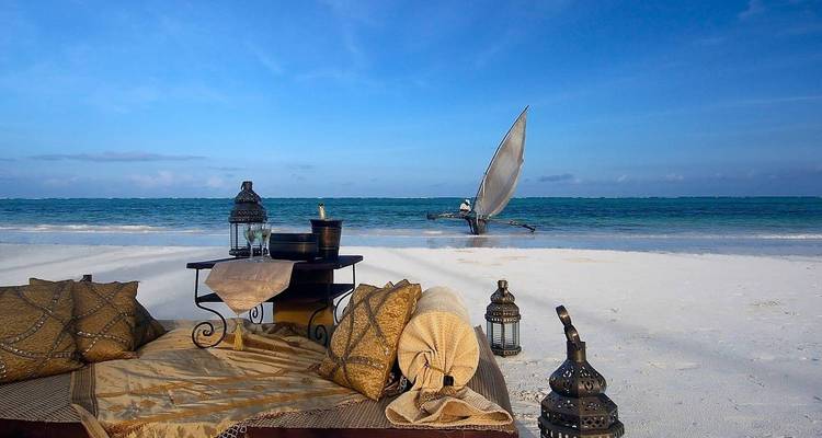 Beach setup with a couch and lanterns, overlooking the ocean.
