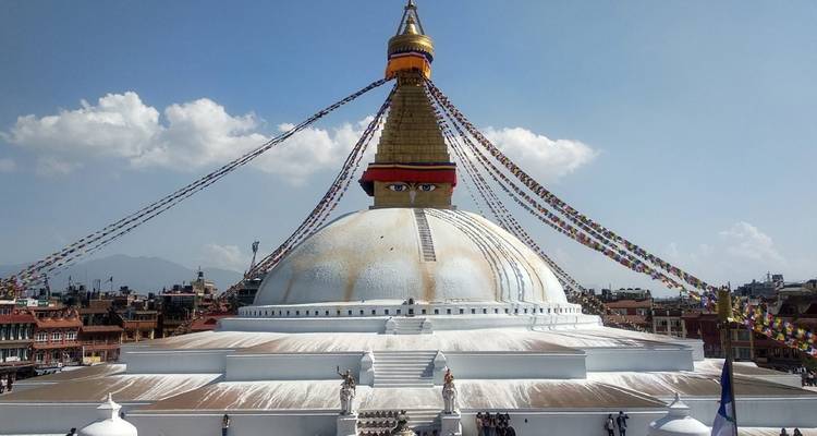 Large stupa with eyes painted on it under a clear blue sky.