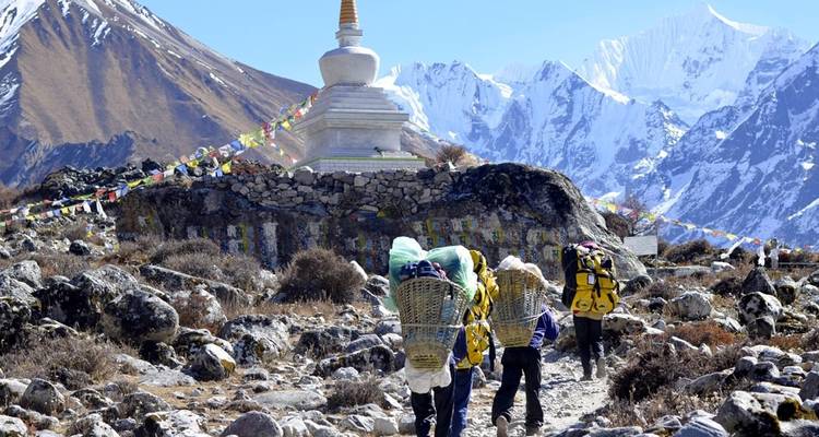 Wanderer, die auf einen Berg-Chorten zugehen, umgeben von schneebedeckten Gipfeln.