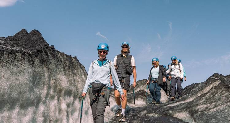 Personas haciendo senderismo en un glaciar con equipo de seguridad y cascos.