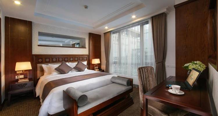 Een luxueuze hotelkamer met een bed en bureau.