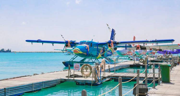 Colorful seaplane parked at a dock over bright blue ocean.