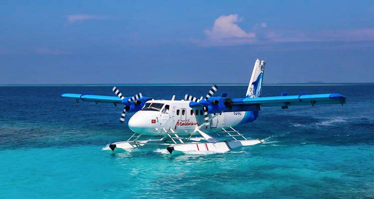 Seaplane taking off from bright blue waters under a clear sky.