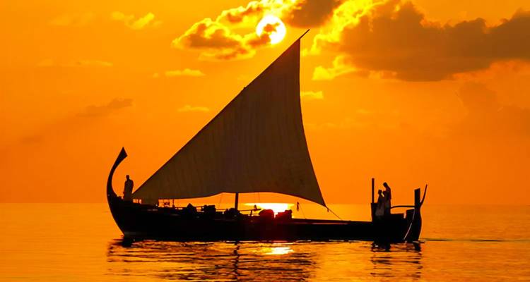 Traditional boat sailing during sunset.