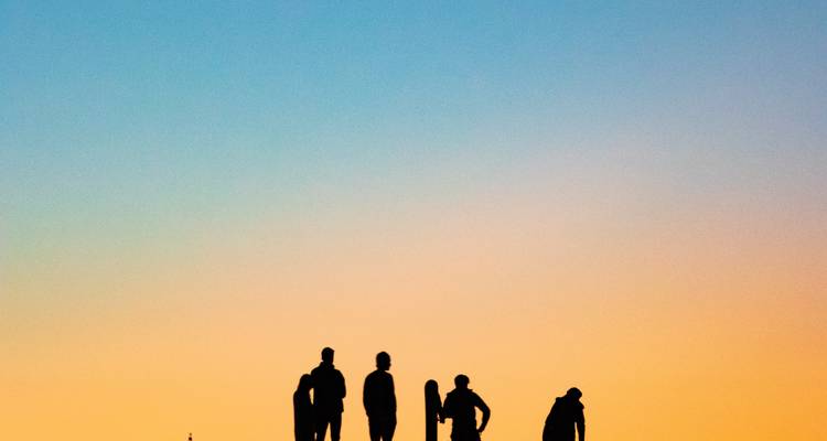 Silhouettes of people against a colorful sunset.