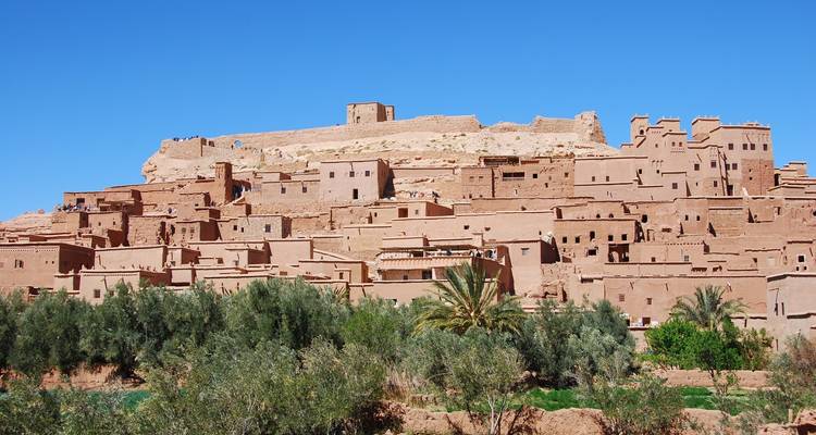 A fortified village in the desert with a bright sky.