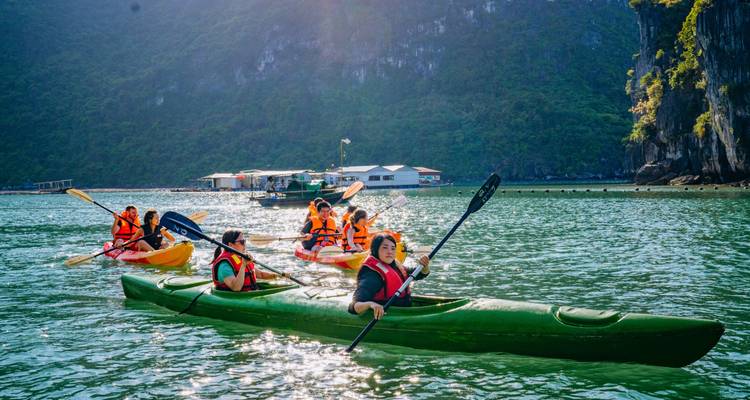 Groep mensen aan het kajakken op het water met kalksteenheuvels.
