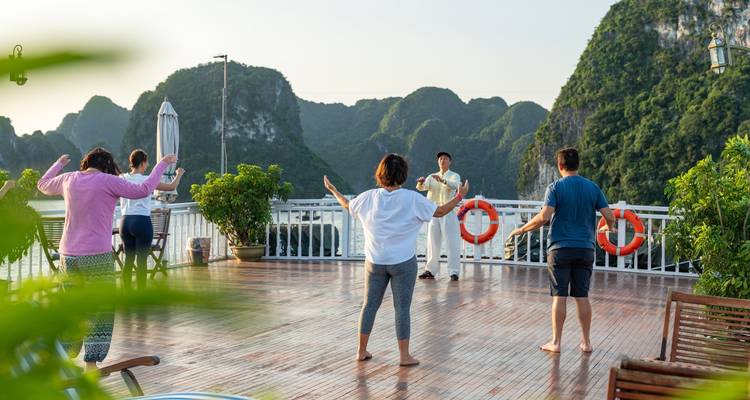 Mensen die Tai Chi beoefenen op een boot met schilderachtig uitzicht.