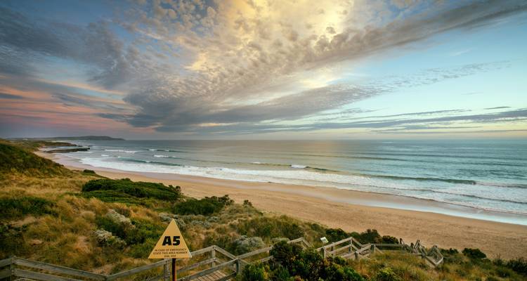 Vue panoramique de plage avec vagues et nuages dramatiques.