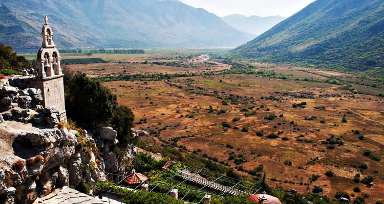 Remote valley with a religious monument set against a vast mountainous landscape.