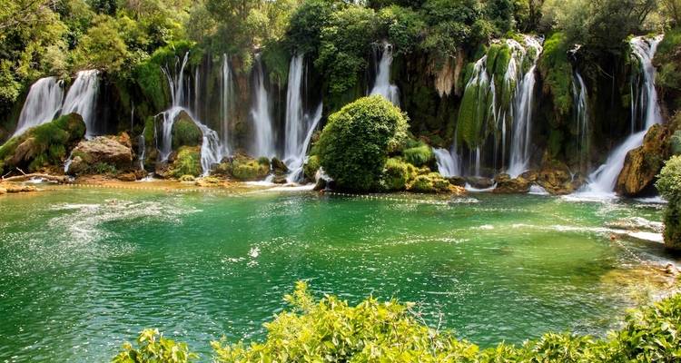 A series of waterfalls cascading into a lush green pool.