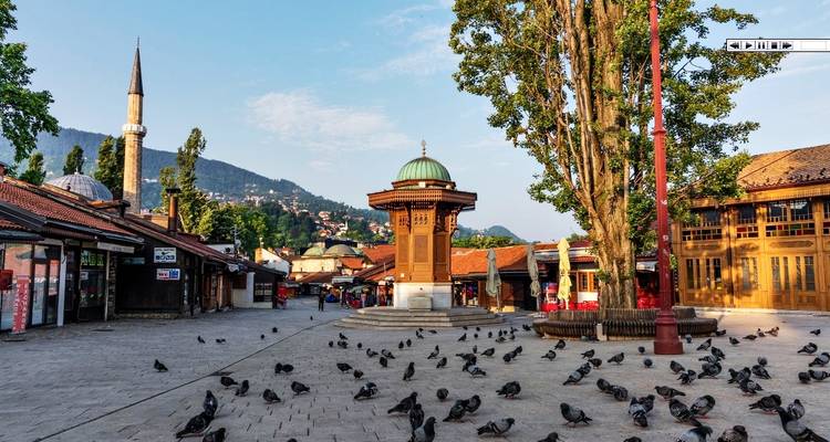 Platz mit Brunnen und Moschee, umgeben von Tauben.