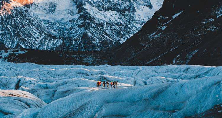 Small group treks across a vast blue glacier surrounded by rugged snowy peaks.