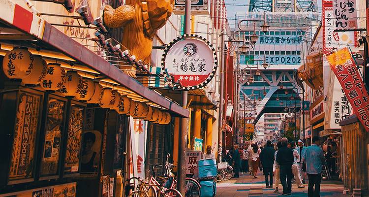 Une scène de rue japonaise animée avec de la signalisation et des gens qui marchent.