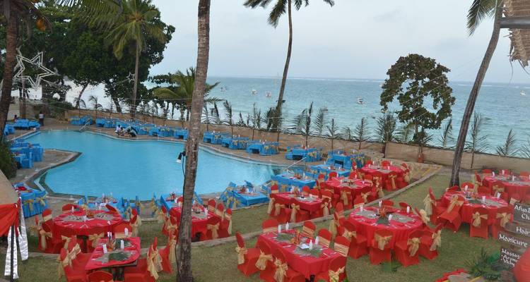 Feestelijke zwembadopstelling met tafels en stoelen bij de oceaan.