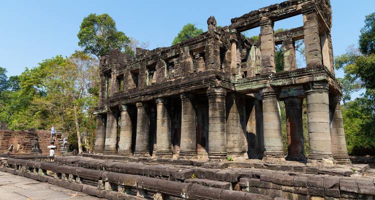 Ancien bâtiment en pierre avec colonnes dans un cadre luxuriant.