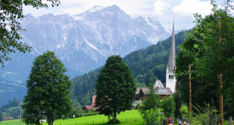 Clocher d'église et montagnes alpines en arrière-plan.