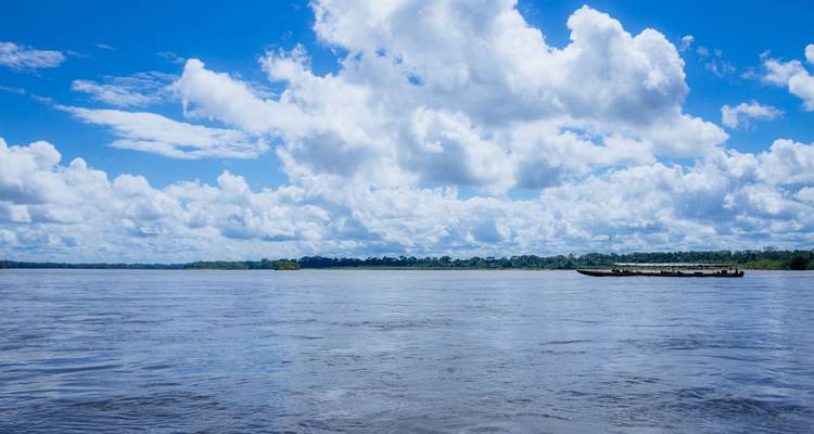 Breiter Amazonas-Fluss unter strahlend blauem Himmel mit hohen weißen Kumuluswolken.